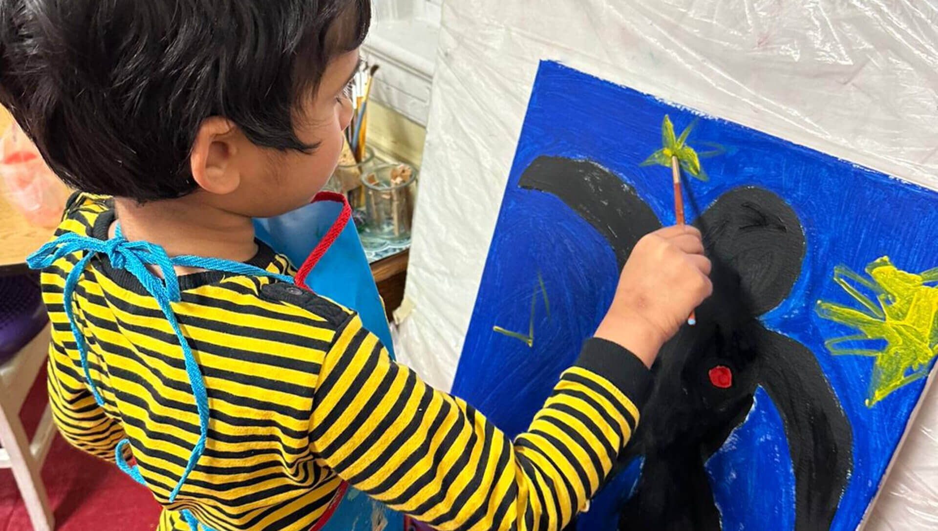 A young boy focused on painting a colorful masterpiece