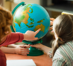 back view of blurred boy pointing at globe near kids and teacher